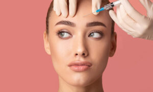 Young Woman Receiving Botox Beauty Injection In Forehead, Studio Shot